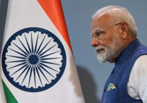 Prime Minister Modi next to an Indian flag.
