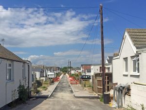 A photo of a street in Jaywick. The houses look cheap and broken, the streets need to be fixed.